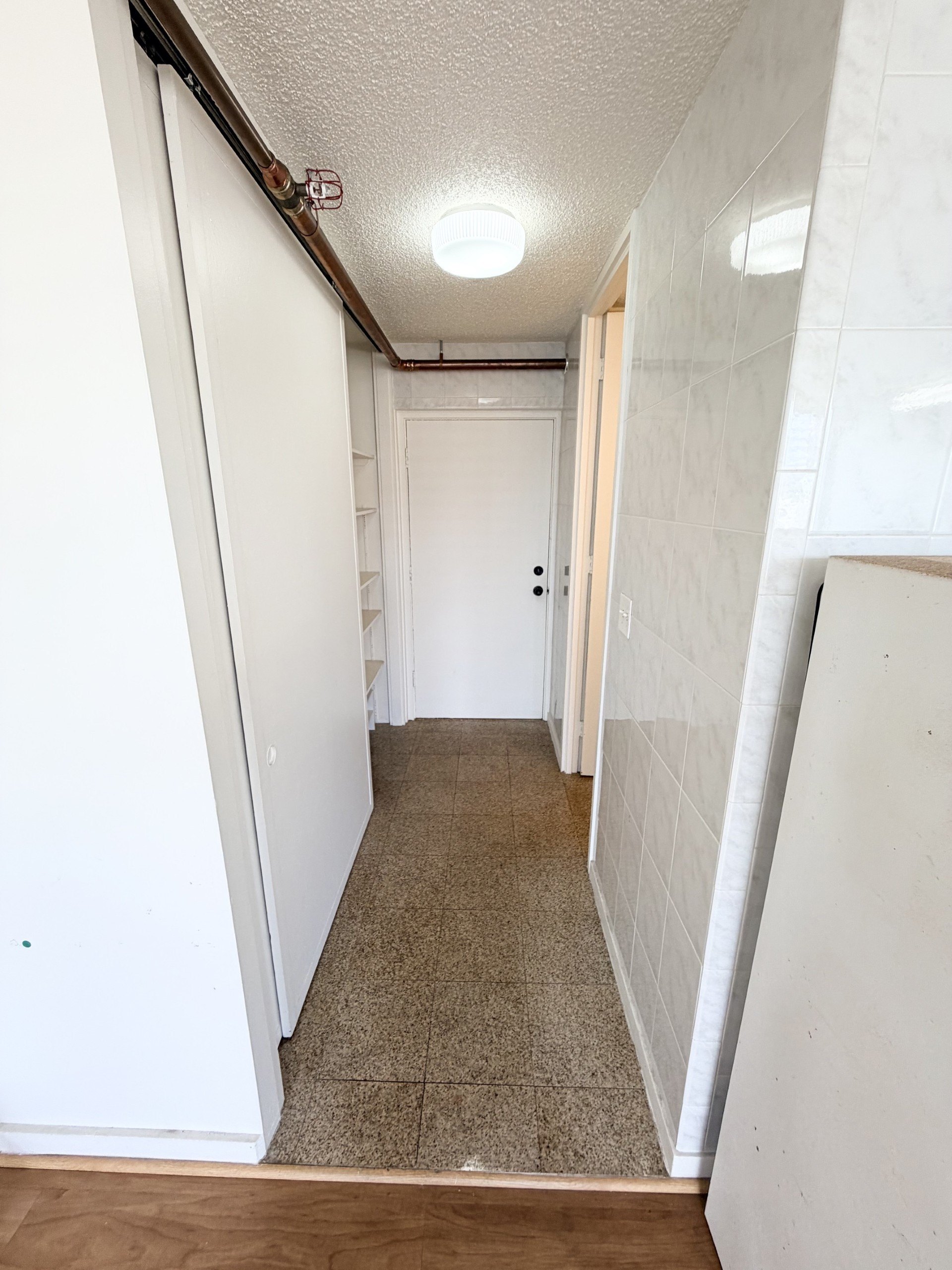 A hallway with a carpeted floor and white walls.